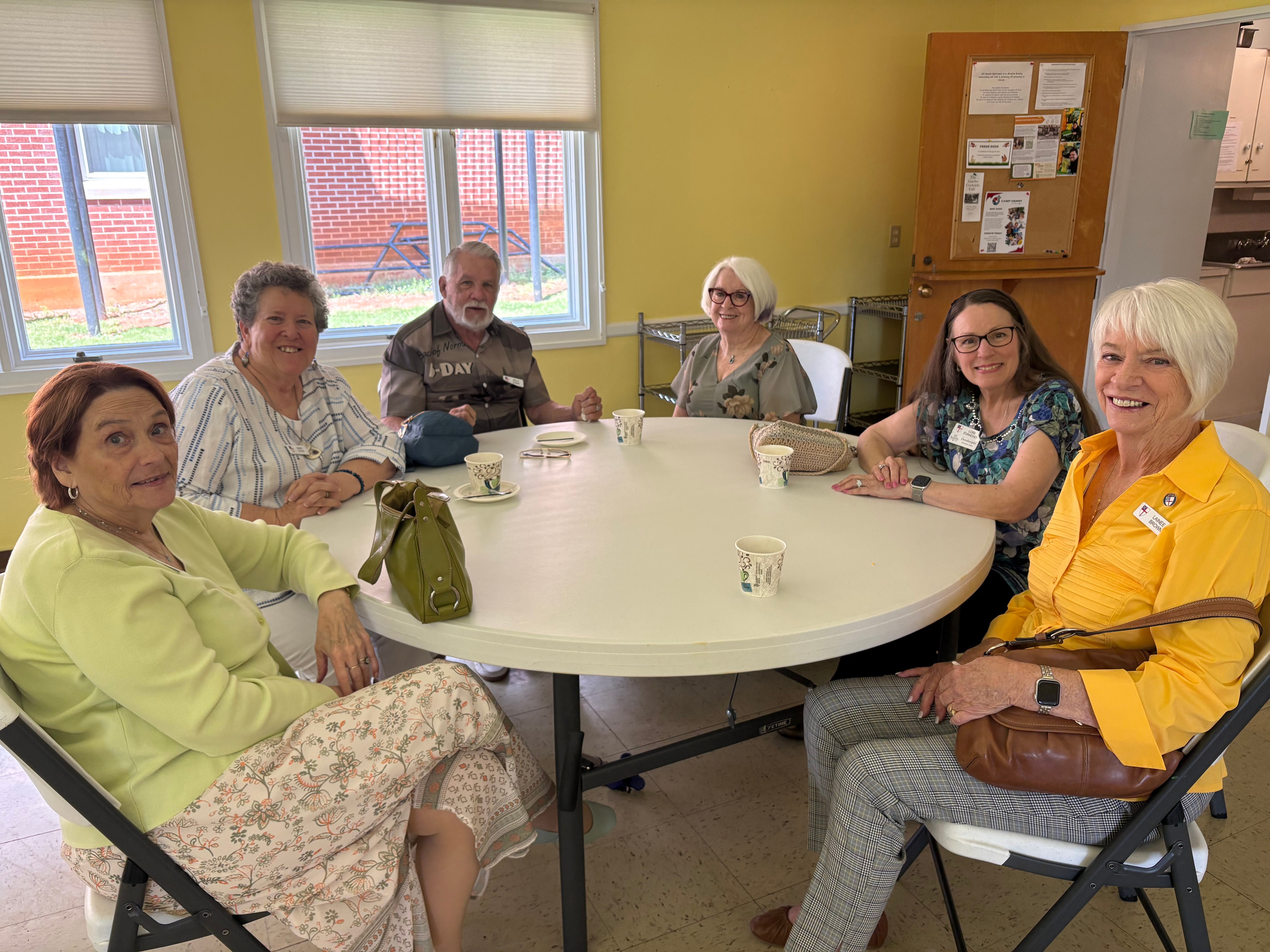 Adults gathered around a table for fellowship and faith formation