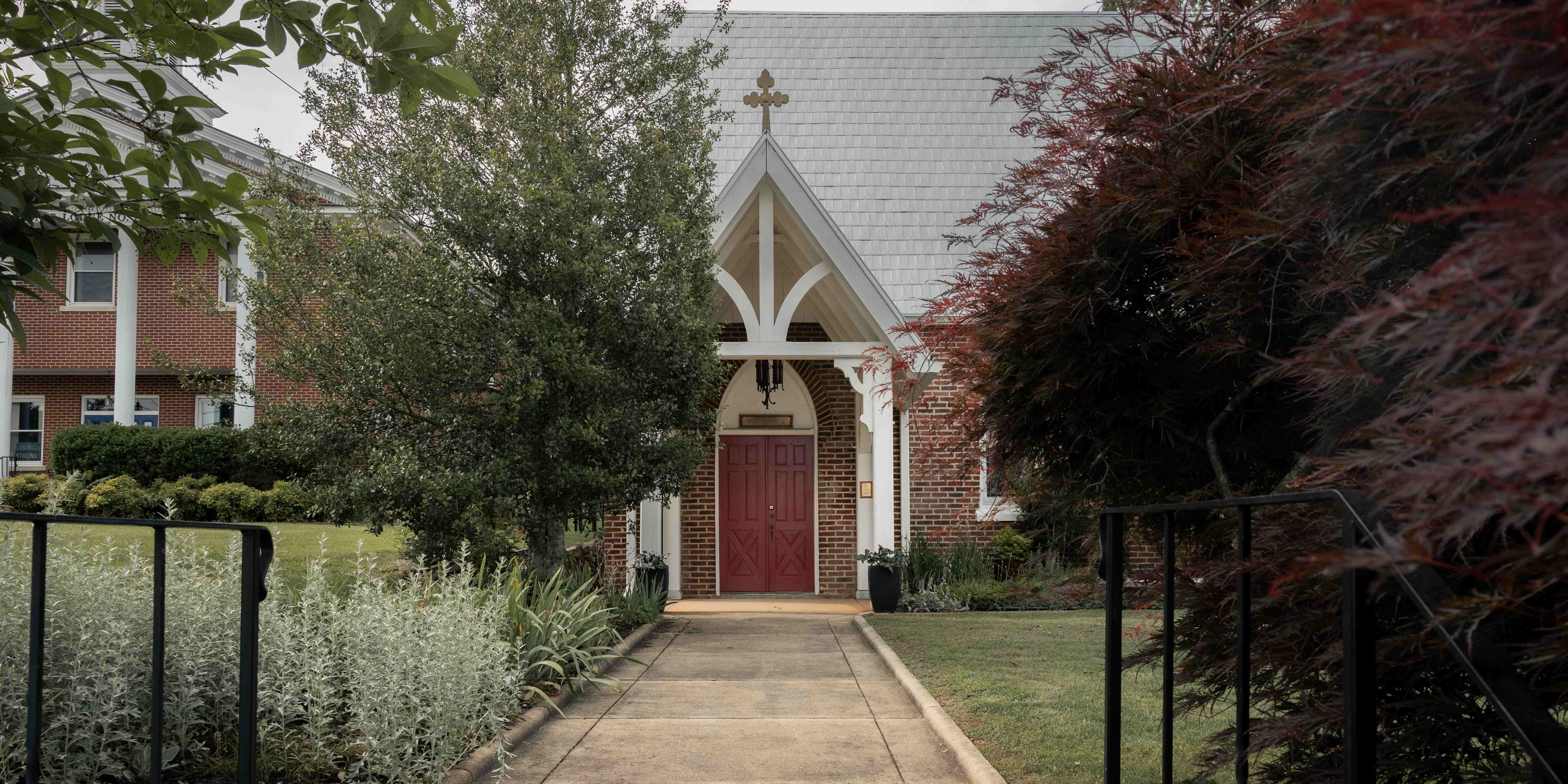 Chapel of Saint Agnes wide exterior view through iron fence, Franklin NC